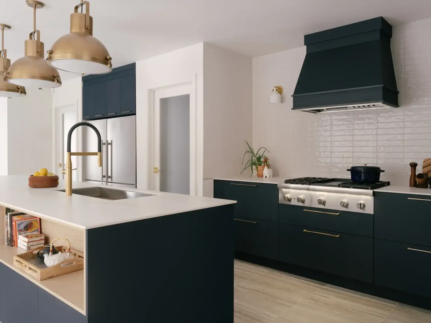 Îlot de cuisine blanc avec évier et robinet doré, hotte décorative et armoires bleu marine – projet Kamouraska.