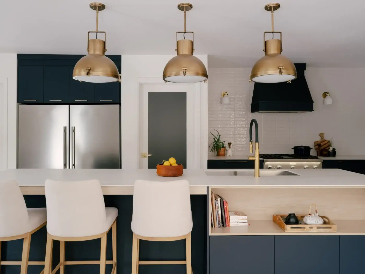 Cuisine bleue avec hotte décorative, comptoir blanc et luminaires dorés de style industriel – design Mathurin cuisines & salles de bains.