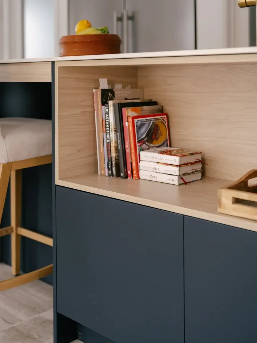 Étagère intégrée en bois clair pour livres de recettes dans îlot de cuisine bleu et blanc – projet Kamouraska.