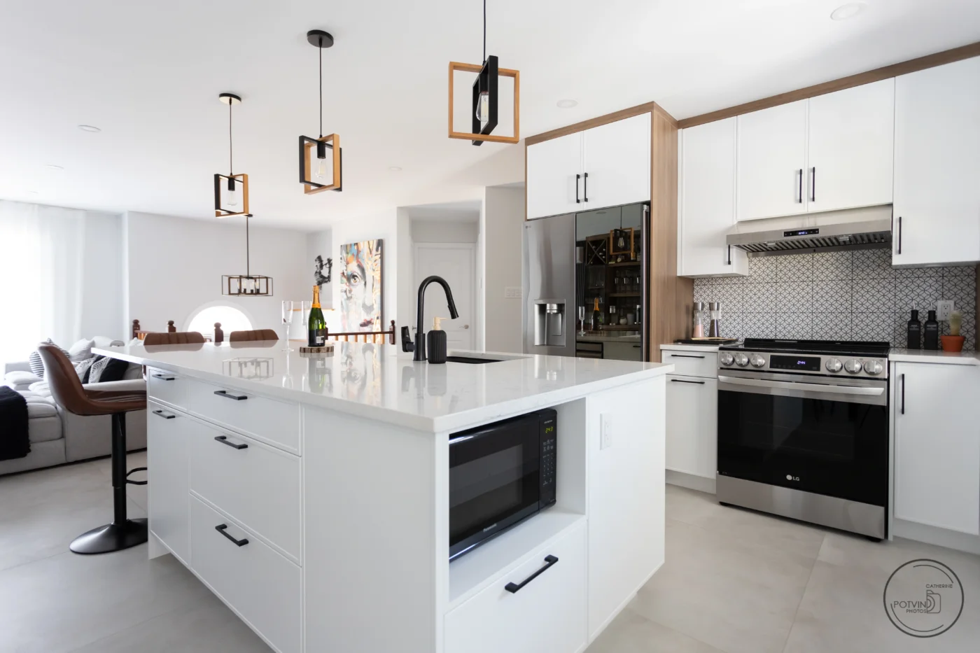 Îlot de cuisine moderne avec micro-ondes intégré, armoires blanches sur mesure, électroménagers inox et hotte encastrée – Armoires Mathurin.