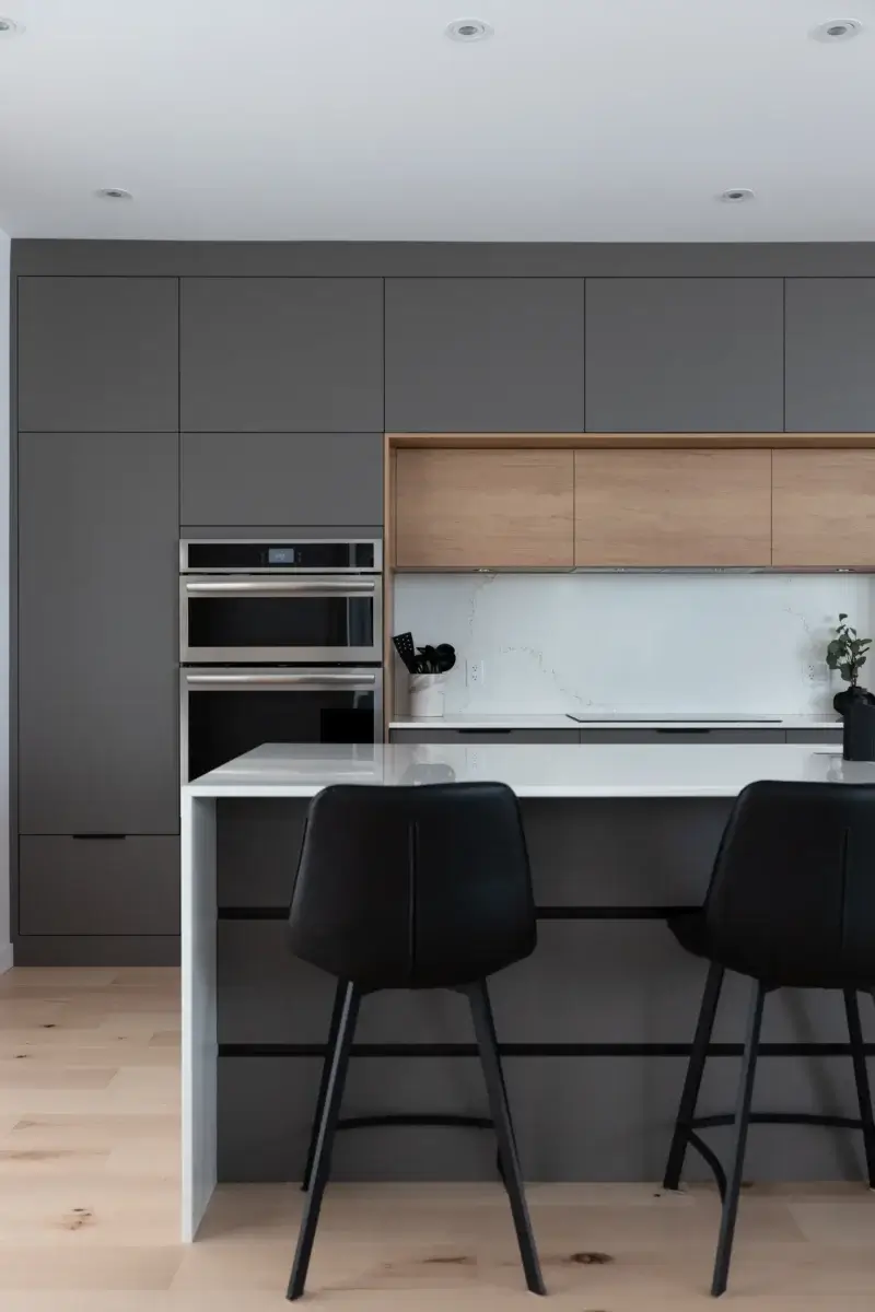 Îlot central blanc avec évier intégré et armoires murales grises et bois clair – cuisine moderne sur mesure.