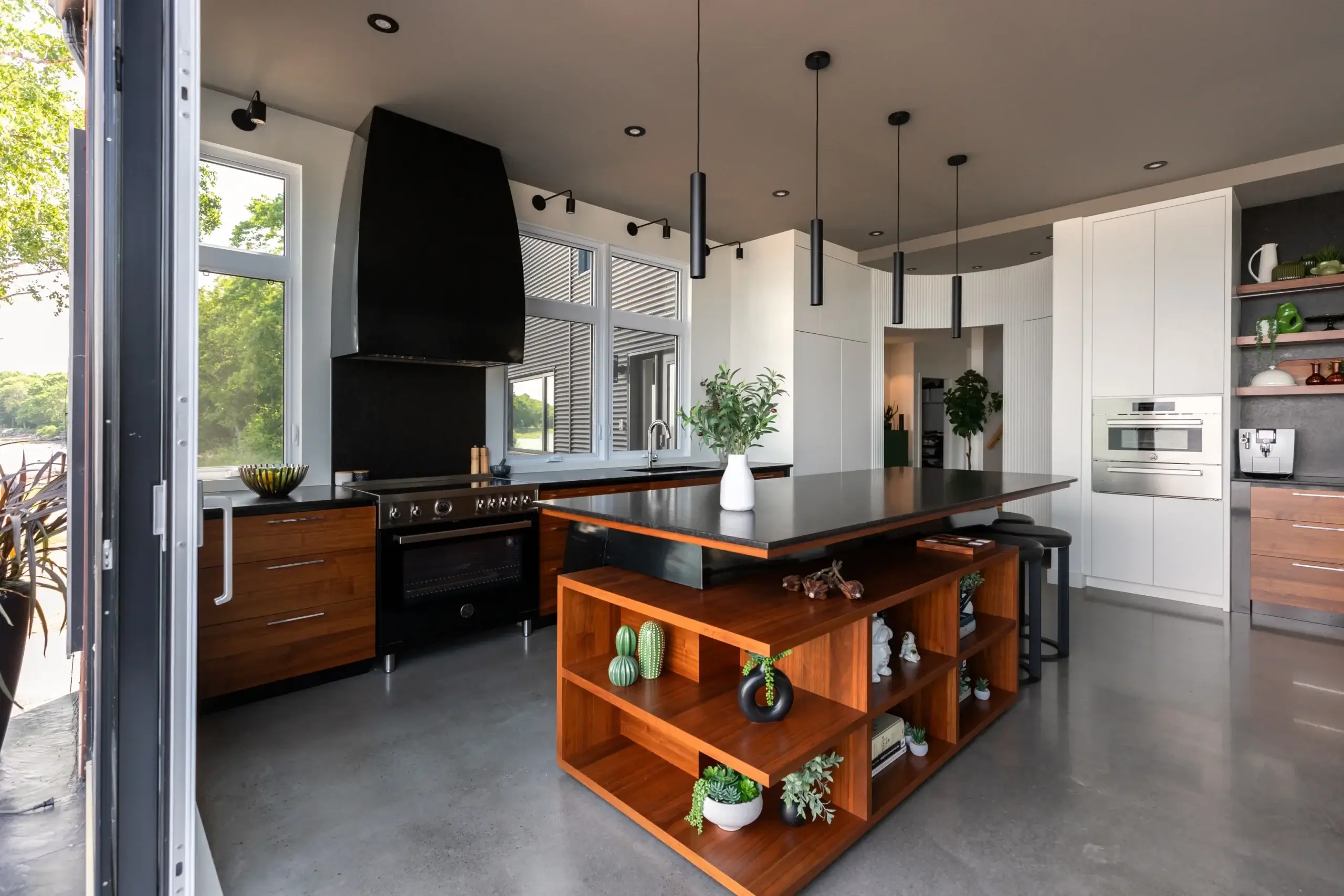 Cuisine moderne avec armoires blanches, four encastré et étagères ouvertes en bois.