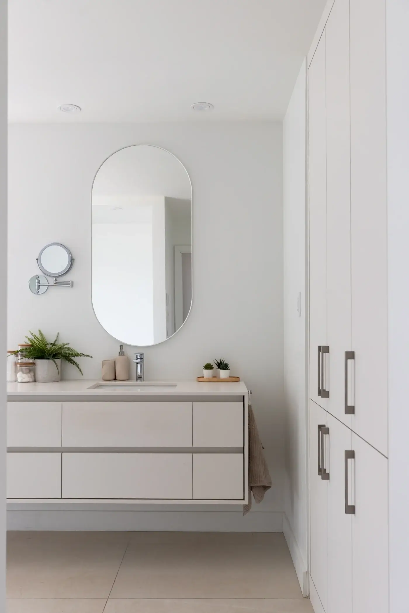 Meuble-lavabo suspendu blanc avec miroir ovale et armoire de rangement.