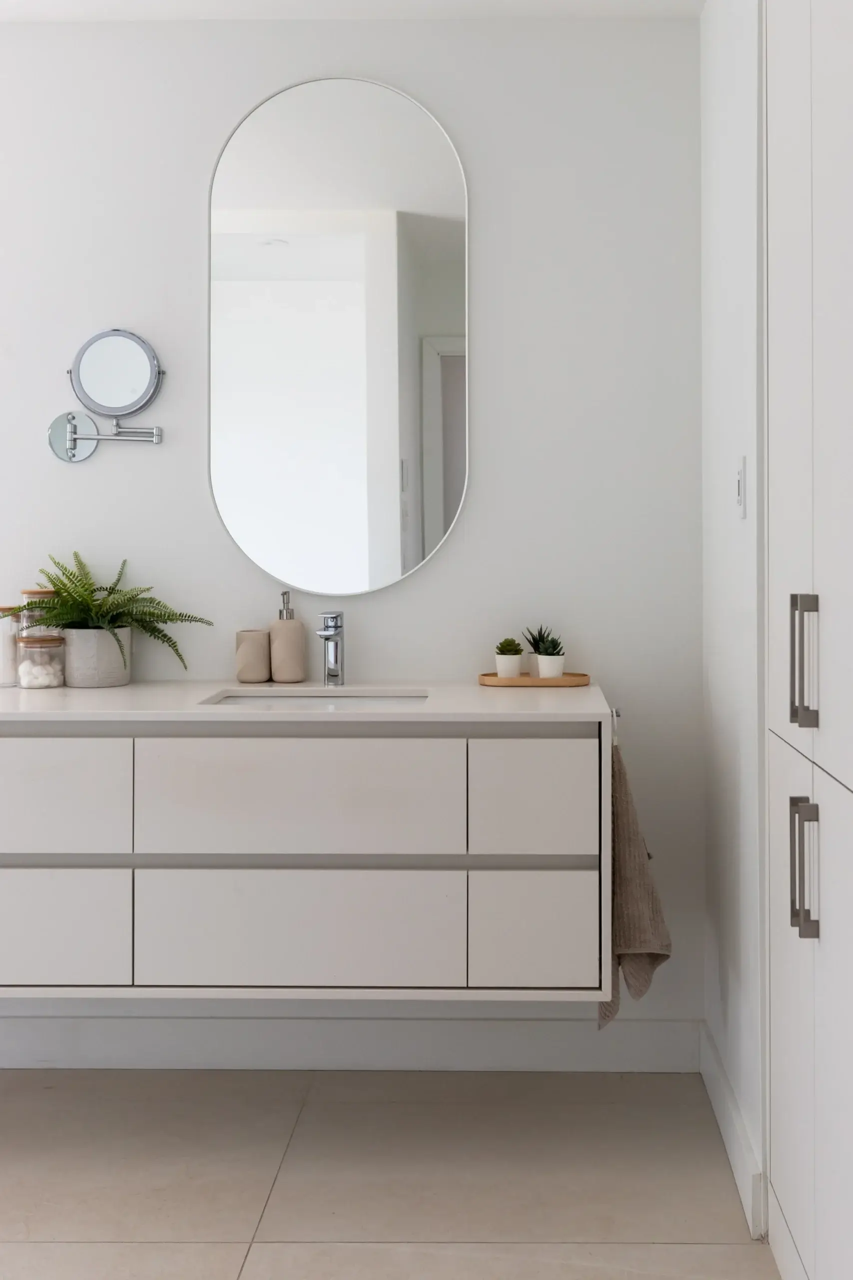 Vanité flottante blanche avec rangement à tiroirs et miroir mural ovale.